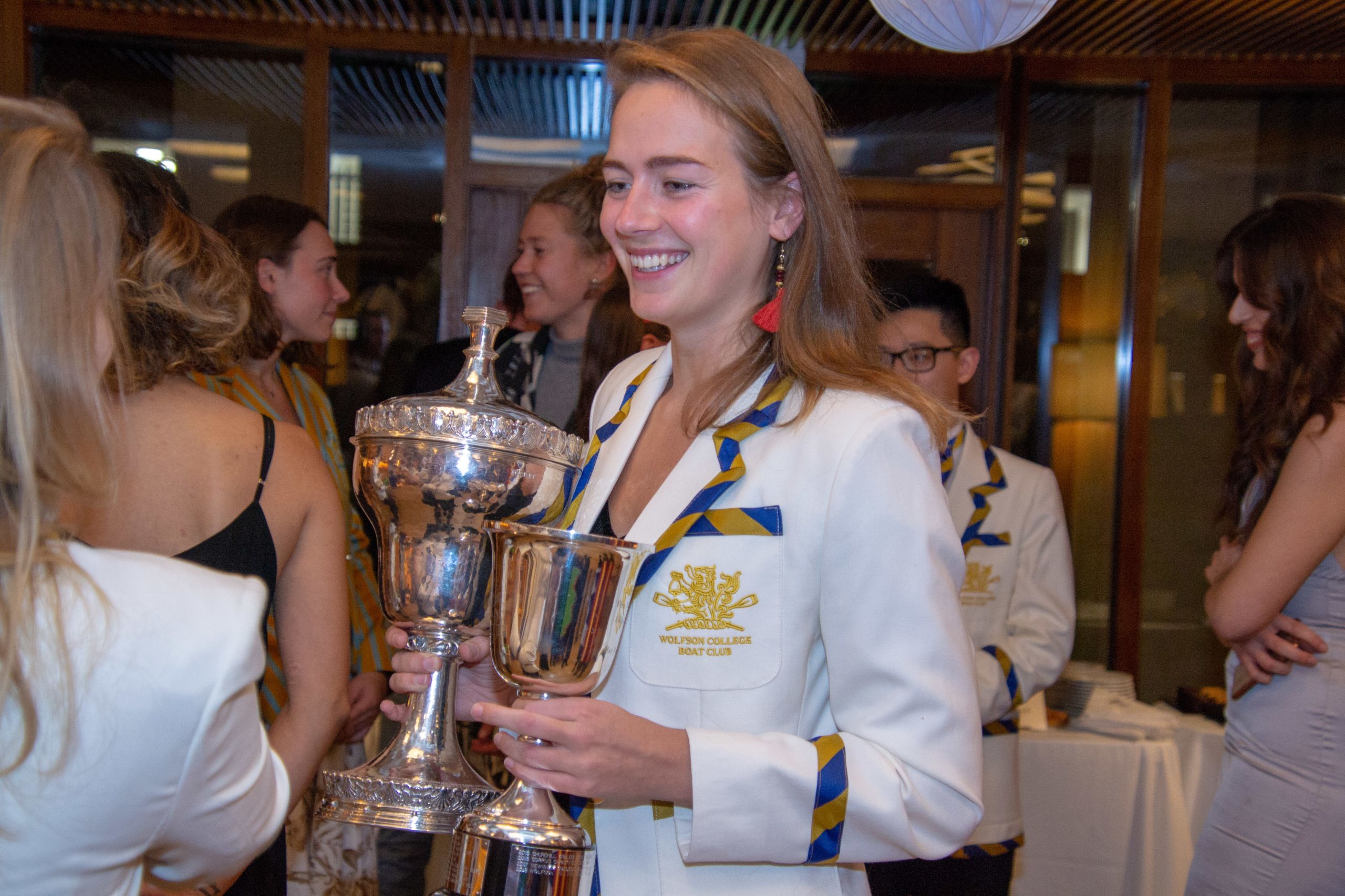 A Wolfson Boat Club member pictured holding the Pegasus and Michell Cups, rowing trophies for the best club on the river for the year and the May Bumps respectively.